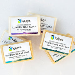 Piled collection of bars of soap, including Kalaya Luxury Bar Soap and Kalaya Nourishing Bar Soap